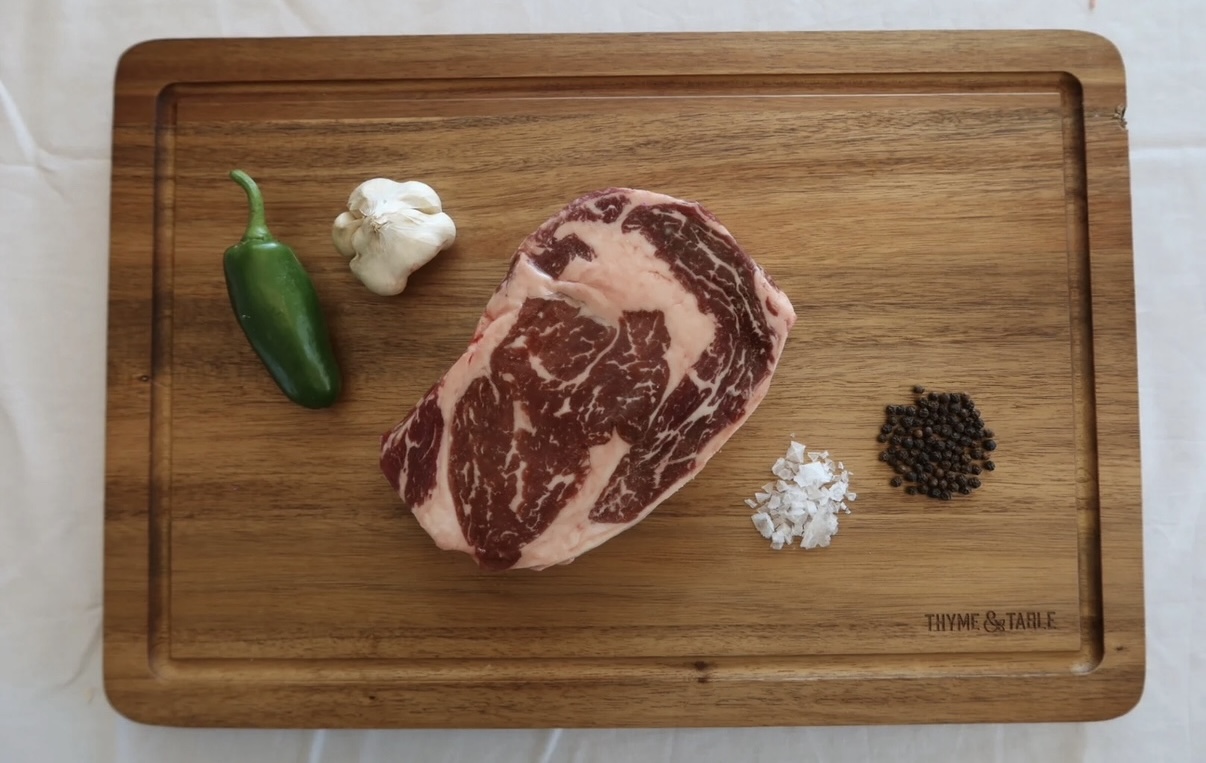 A marbled ribeye on a wooden cutting board